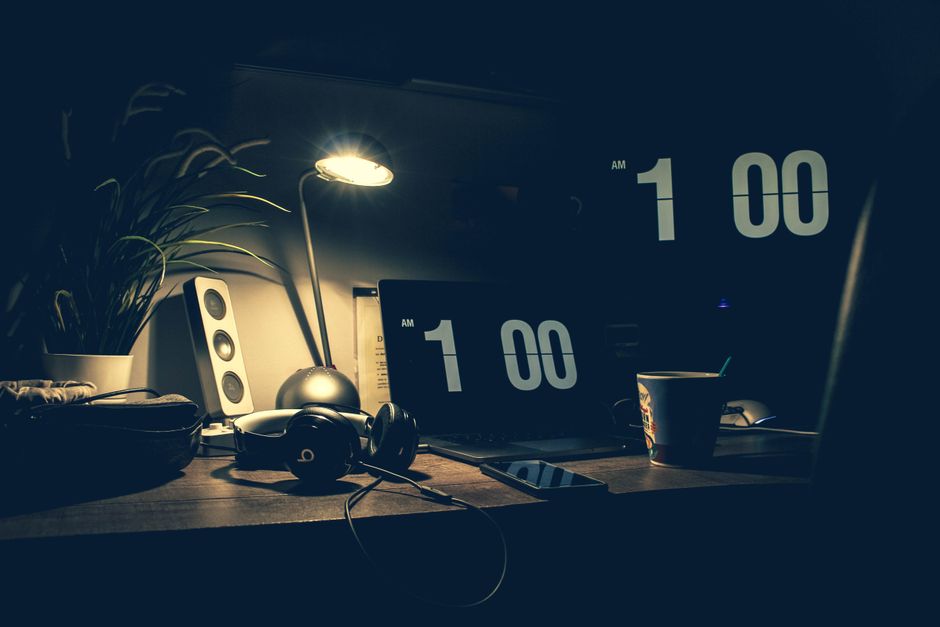 夜1時を指す時計とノートPCが置かれた暗い机